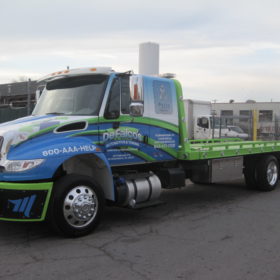 A truck with a blue and green trailer on the back.