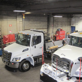 A group of trucks in a warehouse with some work equipment.