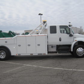 A white tow truck parked in the parking lot.