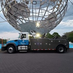 A large truck parked in front of a metal sphere.