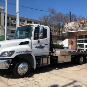 A white tow truck parked in front of a garage.