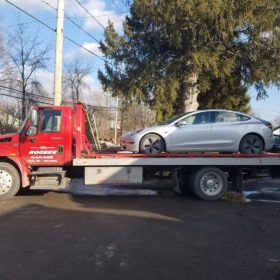 A tow truck is carrying a car on the back of it.