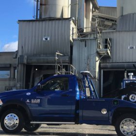 A blue truck parked in front of a factory.