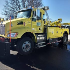 A yellow tow truck parked in the parking lot.