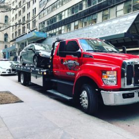 A red tow truck is parked on the side of the road.