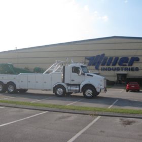 A white tow truck parked in front of a building.